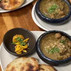 A comforting plate of Amritsari Chole served with fluffy, truffle oil cheese kulchas. The dish is accompanied by a side of homemade kairi achaar for a tangy kick.