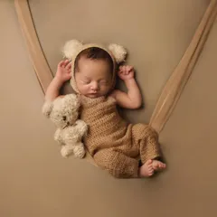 A wider view of the teddy bear theme, showing the newborn nestled in a soft sling. I use simple props like this to create a cozy and secure environment for your baby during their first photoshoot.