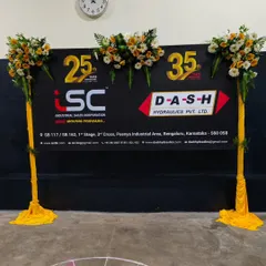 For the 25th and 35th anniversary celebration of ISC and D-A-S-H Hydraulics, I created this branded photo backdrop flanked by decorative stands wrapped in yellow fabric with floral toppers.