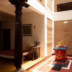 The spiritual heart of the home, this central courtyard features a Tulasi Katte, bathed in sunlight from a skylight. An antique wooden pillar stands as a silent witness, grounding the space in tradition and craftsmanship, creating a serene connection between the sacred and the everyday.