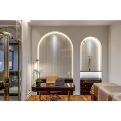 An elegant and luxurious workspace featuring arched wall niches with integrated lighting. The dark wood desk and classic decor create a sophisticated and inspiring environment for work.