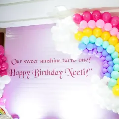 A close-up of the personalized backdrop and rainbow balloon arch from Neeti's sunshine-themed party.