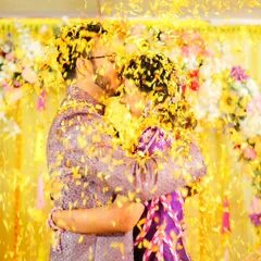 A celebratory kiss amidst a shower of marigold petals. This shot perfectly captures the love and joy of a 'phoolon wali haldi'.