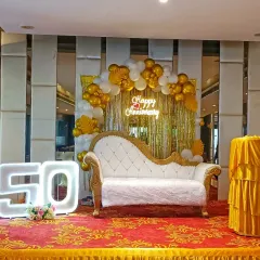 I create special setups for milestone celebrations, like this 50th wedding anniversary. The stage features a gold and white balloon arch, a 'Happy Anniversary' neon sign, and large, illuminated '50' numbers for a perfect photo opportunity.