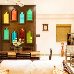 A dining area partition made of jharokha-style arches with colorful stained glass, blending Rajasthani and Bengali craft.