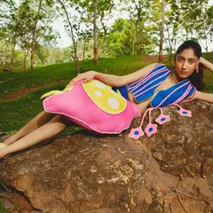 An outdoor campaign shot for the fashion label Sazo.in, featuring a model in a vibrant, playful outfit reclining on a rock in a lush, natural setting. This image demonstrates my ability to create a distinctive mood for brand lookbooks.
