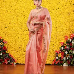 The full view of the peach organza saree against a vibrant yellow backdrop, highlighting its soft, dreamy color.