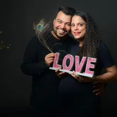 A fun and happy maternity portrait. Using props like the "LOVE" sign and a peacock feather adds a creative and personal element to the session.