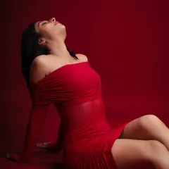 A dramatic and glamorous pose against a rich red backdrop. This shot is perfect for a model's portfolio, showcasing confidence and the ability to convey mood.