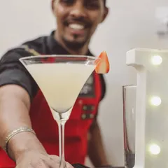 Our bartender presenting a freshly made cocktail with a smile. We pride ourselves on friendly, professional service that makes every guest feel special at your private party.