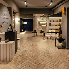 An expansive look at the Paarkhi stone boutique, where a herringbone wood floor harmonises with neutral-toned walls and thoughtfully placed product displays. The design uses open space and strategic lighting to create a serene, gallery-like experience for customers.