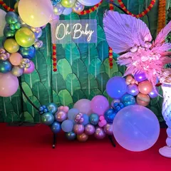 If you prefer a modern aesthetic, I design vibrant balloon-based decorations. This setup features a circular ring with multi-colored chrome balloons, a stylish 'Oh Baby' neon sign, and a tropical banana leaf backdrop for a fresh and trendy baby shower.