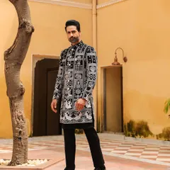 This modern bandhgala features a unique block-print inspired pattern, offering a contemporary take on traditional Indian motifs. Paired with simple black trousers, it creates a sharp, artistic statement for any festive occasion.
