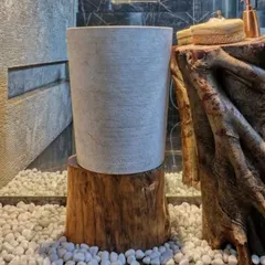 A simple, elegant stone washbasin rests on a raw wooden log base. This detail highlights my philosophy of combining natural, unrefined materials to create moments of quiet beauty and connection to the earth.