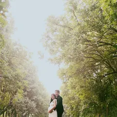 This wide-angle shot captures the couple surrounded by the grandeur of nature. The towering trees frame them perfectly, showing the beautiful environment of our outdoor pregnancy photoshoots.