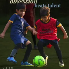 Obsession beats talent. Two young players battle for the ball, showing the competitive fire and determination that we nurture.