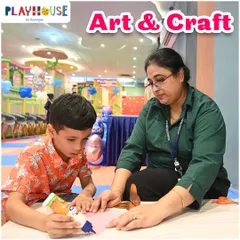 An art and craft session in progress. One of our teachers assists a child with a gluing and cutting project, providing patient, one-on-one instruction.