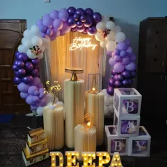 A simple yet elegant purple and white theme. This decoration uses a balloon arch, a neon sign, and 'BABY' display boxes, making it suitable for a baby shower or a first birthday.
