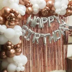 Another example of a birthday balloon decoration, this time with a mix of rose gold chrome and white balloons. The dense balloon garland frames the 'Happy Birthday' foil letters and the shimmery backdrop perfectly.