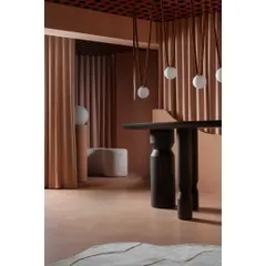 A closer look at the interplay of textures. The smooth micro-topping floor, the fluted wall panels, and the dark, sculptural table create a rich tactile experience that complements the hanging globe lights.