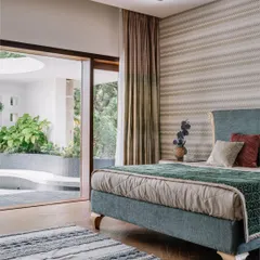 A bedroom that truly brings the outdoors in. The sliding glass doors open completely to a private, sunlit courtyard, extending the living space and filling the room with fresh air. It’s the perfect spot to enjoy a quiet morning coffee.