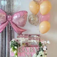 A stunning overview of the 'Baby M' hamper, complete with a large pink bow balloon, confetti balloons, and a cascade of white orchids.