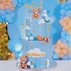 A dreamy three-tiered cake for a teddy bear themed first birthday. Adorned with cute, crowned teddy bears and stars against a soft blue frosting, this cake is as sweet as the occasion.