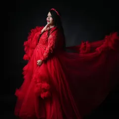 For a bold and dramatic statement, our vibrant red tulle gown is a stunning choice. Set against a simple black backdrop, the color and texture of the dress make for a powerful and unforgettable solo maternity portrait.