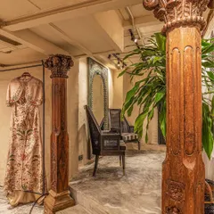 We believe in celebrating materiality and heritage. These graceful vintage wooden columns, salvaged and restored, define the entrance to the changing rooms. They stand against matte greige hand-plastered walls, showcasing our signature blend of raw textures and refined historical elements.