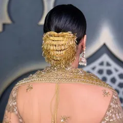 Elegance is in the details. This polished, low bridal bun is finished with a statement golden hair accessory, creating a look that is both regal and contemporary for a Sangeet or wedding ceremony.
