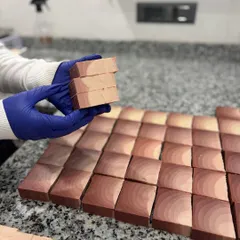 Holding up a stack of freshly cut soap bars. The natural color and texture of these bars come from the plant-based ingredients we use.