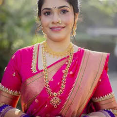 The quintessential Maharashtrian bride in a vibrant pink Paithani saree. Her look is completed with traditional gold jewelry and a simple, elegant hairstyle.