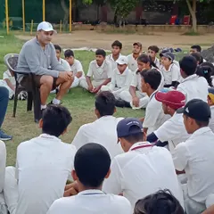 Seated informally on the field, our founder creates a comfortable environment for young players to learn and absorb lessons on cricket and life.