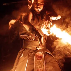 A close-up portrait of our male fire artist manipulating fire poi. The image captures the intensity and control required for technical fire spinning.