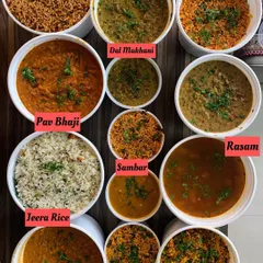 A colorful array of some of my most requested dishes. You can see comforting Dal Makhani, spicy Pav Bhaji, tangy Sambhar, and flavorful Tawa Pulao, all ready to be packed.