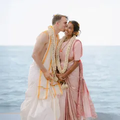 A tender kiss on the cheek against the serene backdrop of the open sea. This image from a beautiful waterside Hindu wedding captures a moment of sweet affection and quiet joy.