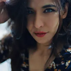 A close-up portrait that captures a playful and confident expression. The way she runs her hand through her hair adds a natural, unposed feel, while the tight framing on her face and bright eyes makes the image instantly engaging.