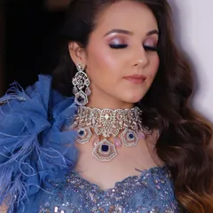 This shot showcases the complete cocktail look, including the soft waves in the hair and the elegant feathered shoulder detail of the gown. The makeup ties the entire glamorous look together.