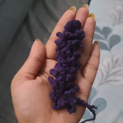 A detailed, in-hand view of one of my crocheted lavender stems. I use a rich purple yarn and a special stitch technique to create the textured look of real lavender buds. These add a lovely touch of color and detail to my floral arrangements.