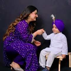 A mother shares a sweet, interactive moment with her son, who is dressed in a traditional kurta and turban. This photo highlights the beautiful bond between mother and child.