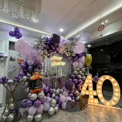 For this 40th birthday, we went for a classy and fun theme. The setup includes a balloon arch in purple and silver, a shimmer curtain backdrop, large marquee numbers, and even a fun whiskey bottle foil balloon to match the party vibe.
