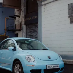 A classic Volkswagen Beetle in a charming pastel blue, parked in a quiet lane in Mumbai. This photo captures the car's iconic and friendly personality, showcasing it as a piece of urban art.