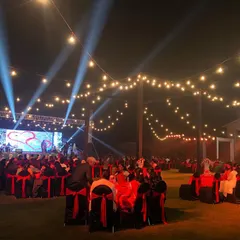 A wide-angle view of a large-scale corporate gala night we organized in Lonavala. The setup includes a professional stage with a large LED screen, truss lighting, and elegant round table seating for hundreds of guests under a canopy of string lights.