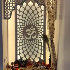 This intricate pooja unit features a backlit "Om" symbol on a jali-patterned screen. The design provides a serene and divine focal point in the home.