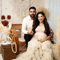 A classic portrait of the couple in a boho-inspired studio setup. The macrame wall hanging, pampas grass, and neutral-toned outfits create a warm and inviting atmosphere.
