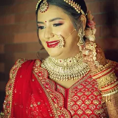 A beautiful close-up portrait of the bride, capturing her happy expression and traditional jewelry like the nath and maang tikka.
