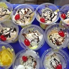 Individual cups of ice cream sundae, garnished with chocolate sauce and a cherry. This is a simple yet delightful dessert option that is loved by guests of all ages.