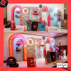 A full view of our mechanic-themed party for Srijay's first birthday. The setup includes a tool-covered backdrop, a light-up gas station arch, and a cool red car prop.