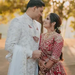 A classic couple portrait where the bride and groom share a look of love. The natural, outdoor setting provides a beautiful, soft backdrop for their traditional red and white outfits.
