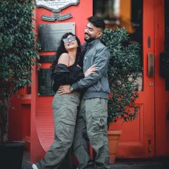 A fun and stylish shot of a couple in matching cargo pants, embracing in front of the iconic red entrance of 'The Biere Club' in Bangalore.